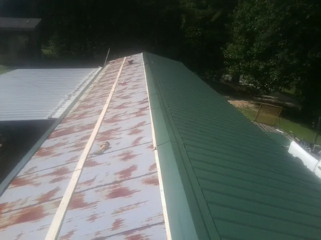 Old rusted panels beside newly installed green metal roofing — Wind Damage Roof Repair by Roofing Brothers in Abbeville